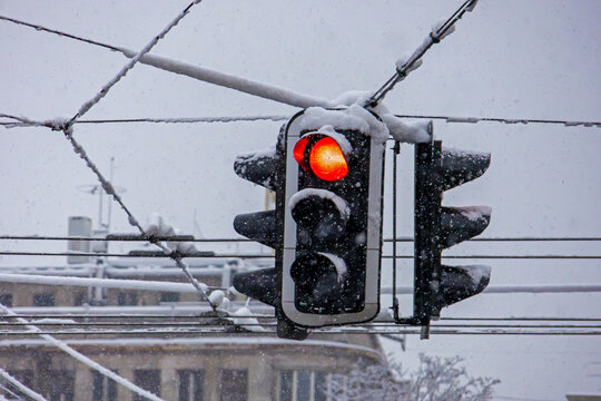 Traffic light hanging outside from sky on local urban street in winter under snow