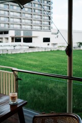 Fototapeta premium A serene view of a grassy field from a balcony with a coffee drink on a wooden table