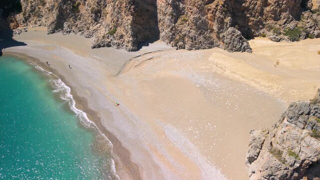 Aerial 70mm fast flight over Agiofarango beach, Crete, Greece. Drone dynamic view with camera down on empty beach, sharp turn to reveal reverse rocks and turquoise sea horizon. Cinematic 4k
