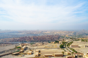 Obraz premium A wide panoramic view of the sprawling city of Cairo, Egypt, seen from the elevated vantage point of Mokattam Mountain under a hazy sky.