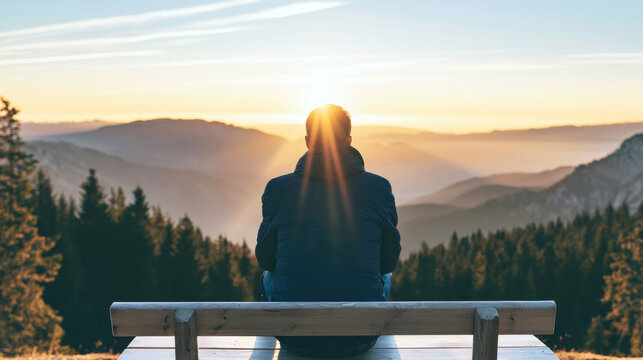 Person sitting on a wooden bench, observing a vast mountain landscape at sunrise, feeling peace and freedom