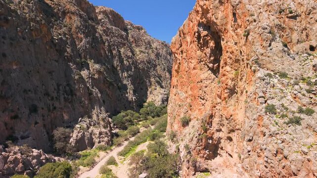 Aerial view of Agiofarango canyon, red dome church and cave hole, Crete Greece. Drone vertical flight from chapel to big cave, then pan along gorge to wild beach with turquoise water. 4k scenic video