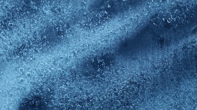 Extreme macro close-up of cracked blue melting ice texture in time lapse. Abstract frozen water surface with translucent crystal patterns, condensation and thawing details in studio lighting.
