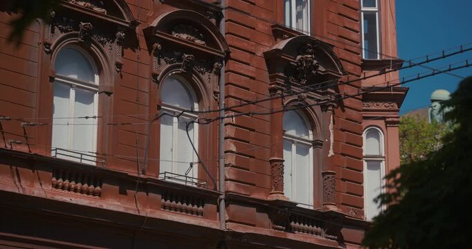 Close-up of ornate historic building facade with windows and tram wires in Zagreb, Croatia.
