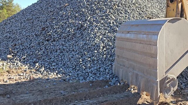 Heavy machinery moves gravel at construction site in sunny weather