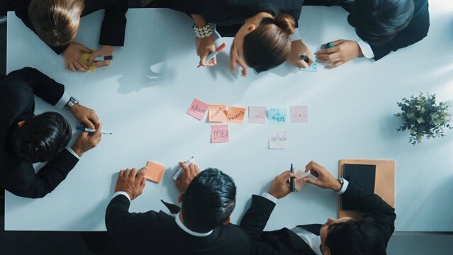Top down aerial view of businesswoman give sticky notes to participant before start meeting. Young beautiful project manager prepare to discuss and brainstorm marketing idea at boardroom. Directorate.