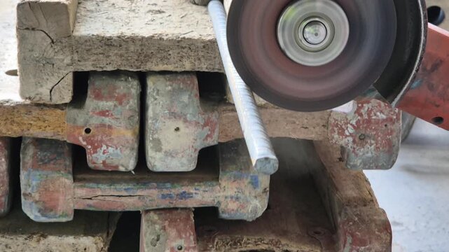 Slow motion close up of a shower of sparks flying from an angle grinder cutting through a metal reinforcement bar.