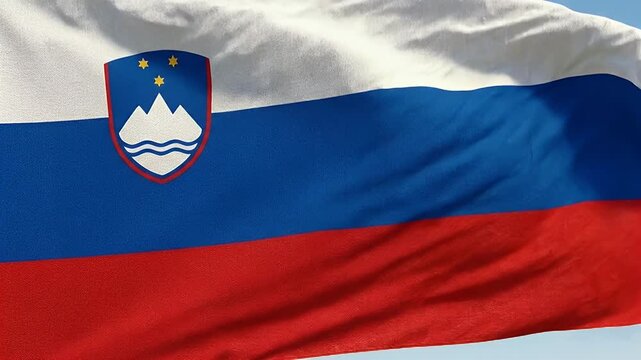 The video captures the vibrant colors of the Slovenian flag fluttering in the breeze. The flag features horizontal stripes of white, blue, and red with the national coat of arms positioned near the