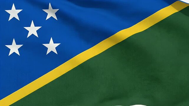 A close up shows the national flag of the Solomon Islands waving gently. The flag features a blue field with five white stars, divided diagonally by a yellow stripe over a green field.