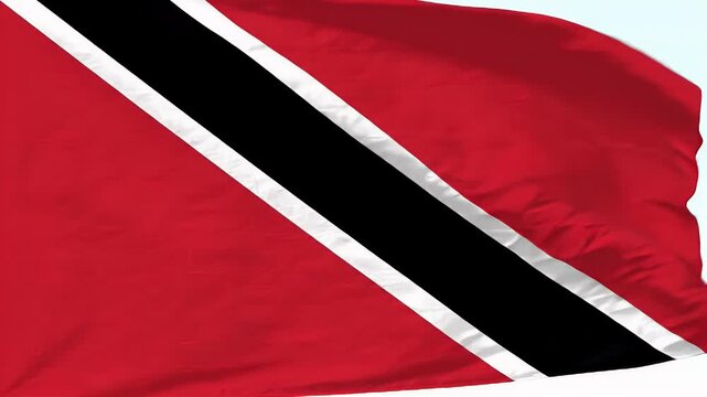 A vibrant video of the Trinidad and Tobago flag waving in the air. The flag features a bold black diagonal stripe bordered by white bands on a red field, symbolizing strength and courage.