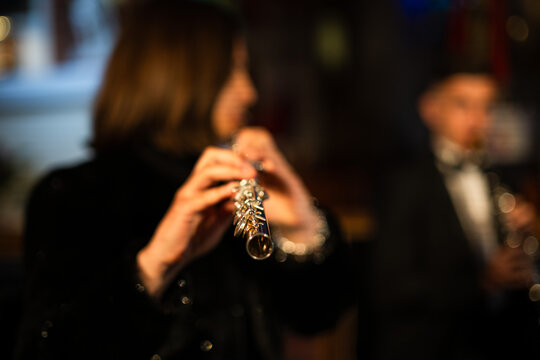 A detailed close-up shot of a female flutist's hands playing the keys of a silver transverse flute, showing intricate finger placement during a performance.