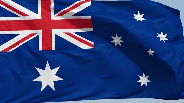 A close-up shot of the national flag of Australia waving gently. The flag features the Union Jack in the upper left corner and the Commonwealth Star and Southern Cross constellation on a blue