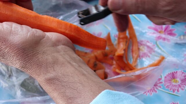 Hands peeling fresh carrot with metal vegetable peeler video