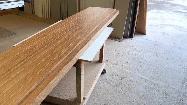 Finished wood veneer panels stacked on a workbench in a carpentry workshop.