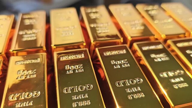 Gold bars stacked in rows show shining details of their weight and purity in a close view of the investment asset