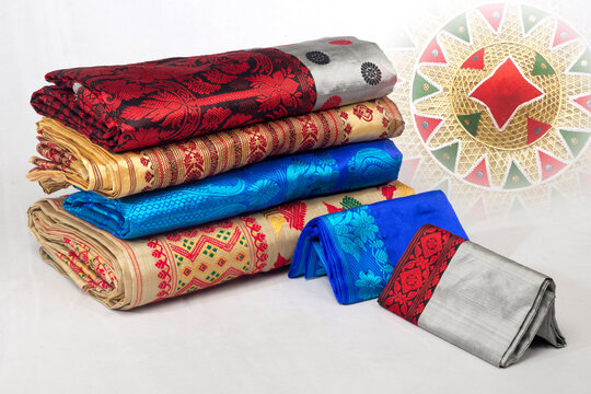Traditional Assamese silk mekhela chador fabrics with colourful woven floral and geometric patterns displayed in a textile shop