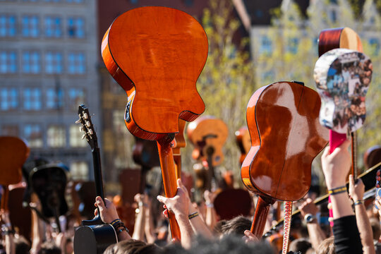 Close-up view of a crowd raising acoustic guitars and ukuleles into the air during an outdoor music event in Wroclaw, Poland.