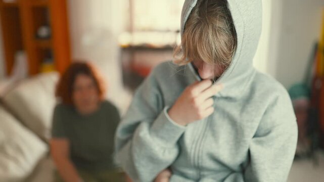 Introverted teenager hiding face with hoodie at home