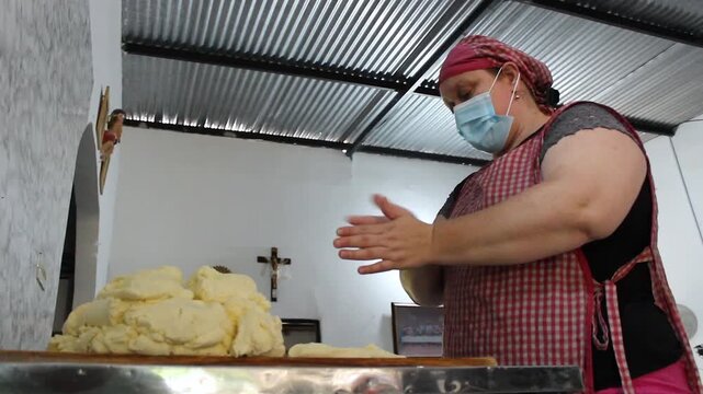 Portrait of a Colombian woman wearing an apron and face mask preparing achira biscuits with flour on a table inside her home in Yaguara, Huila, Colombia. Concept of Colombian food and handmade 