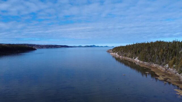 Aerial drone video capturing the vast St. Lawrence River along the Rimouski coast with panoramic views toward Bic National Park and dramatic overcast clouds in Quebec, Canada.