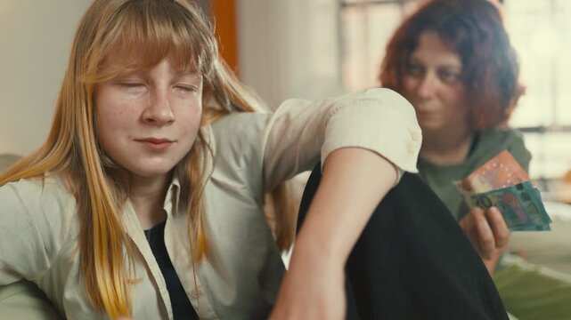 Greedy teenage girl winning money playing a board game with friend