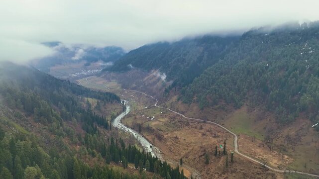 Aerial pullback through clouds revealing the vast Lidder river valley.