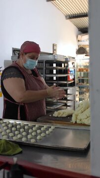 A Colombian woman wearing an apron and face mask is preparing achira biscuits with corn dough in a kitchen in Yaguara, Huila, Colombia. Concept of colombian food 