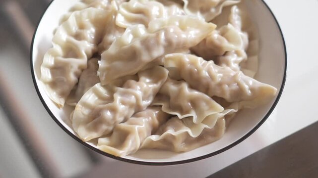 Steaming Chinese Dumplings in a White Bowl on a Wooden Table