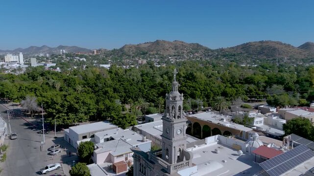 The ornate white bell tower of the Nuestra Se&ntilde;ora del Carmen Parish Church in Hermosillo, Sonora (Mexico). In the background, the iconic Cerro de la Campana rises, its communication antennas visible.