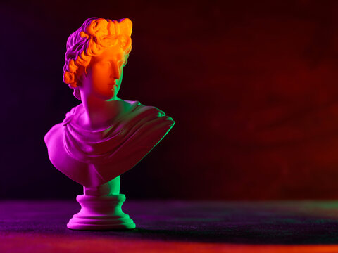 Classical bust sculpture illuminated with vibrant neon orange purple and green lighting effects