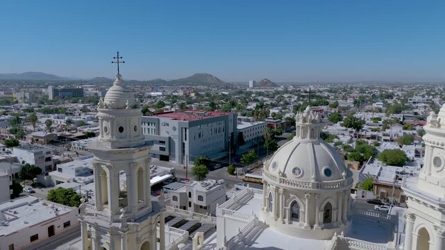 The Metropolitan Cathedral of Hermosillo, Sonora (Cathedral of the Assumption), with its neoclassical and Baroque towers and central dome. The surrounding plaza, with lush trees and a bandstand.