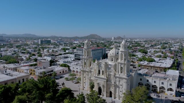 The Metropolitan Cathedral of Hermosillo, Sonora (Cathedral of the Assumption), with its neoclassical and Baroque towers and central dome. The surrounding plaza, with lush trees and a bandstand.