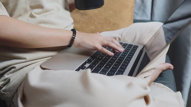Woman performing remote work by typing and scrolling on a laptop, a device crucial for modern day business, online education, and staying connected from her home office setup