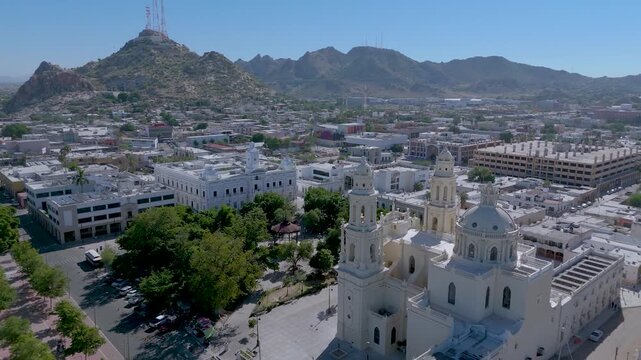 The Metropolitan Cathedral of Hermosillo, Sonora (Cathedral of the Assumption), with its neoclassical and Baroque towers and central dome. The surrounding plaza, with lush trees and a bandstand.