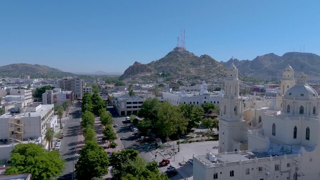 The Metropolitan Cathedral of Hermosillo, Sonora (Cathedral of the Assumption), with its neoclassical and Baroque towers and central dome. The surrounding plaza, with lush trees and a bandstand.