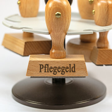 Holzstempel mit dem Text Pflegegeld