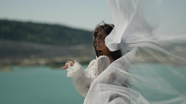  Happy bride stands by the water, her veil fluttering in the wind. Happy bride concept.