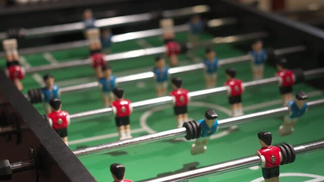 Foosball Table with Red and Blue Player Figures on Green Field, Indoor Arcade Game Setup