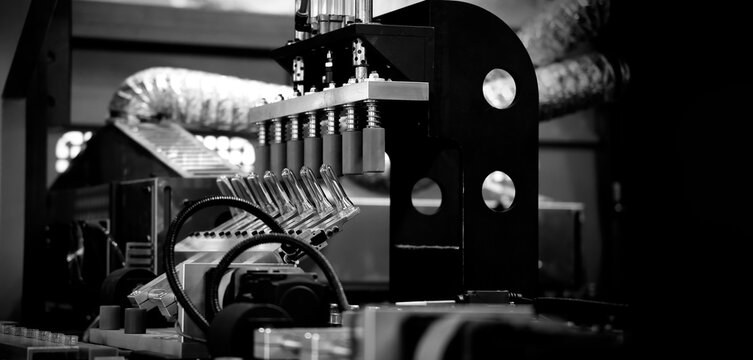 PET bottle machinery. Automated plastic bottle manufacturing machine operating on factory production line. Robot machine for bottle preform or forming packaging high speed plastic container production