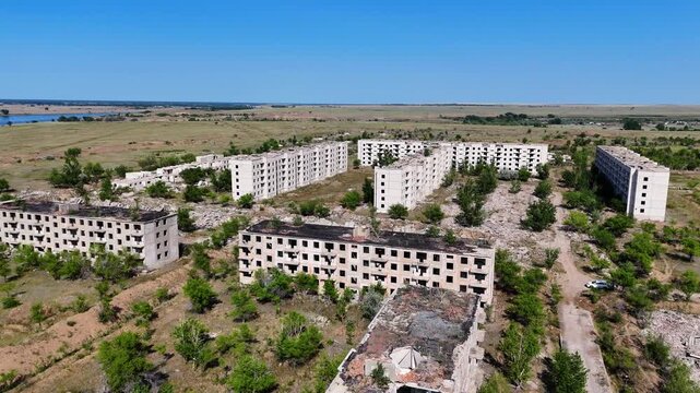 Aerial drone flight over multiple ruined Soviet panel buildings in the abandoned military ghost town of Chagan. Footage captures the emptiness and devastation of a former secret USSR site in Kazakhsta