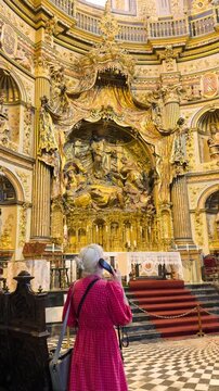 emale traveler using an audio guide while exploring the ornate interior of a historic church in &Uacute;beda, Spain. 