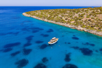 High angle shot of a boat anchored in the clear blue Aegean Sea near Elounda, Greece © whitcomberd