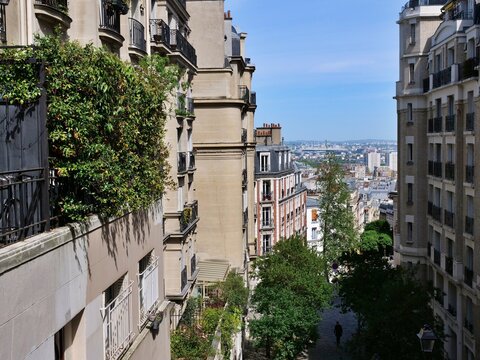 High angle view looking down a steep, picturesque street in the Montmartre
district of Paris. Classic Haussmann-style apartment buildings with wrought-iron
balconies and lush green terrace plants line