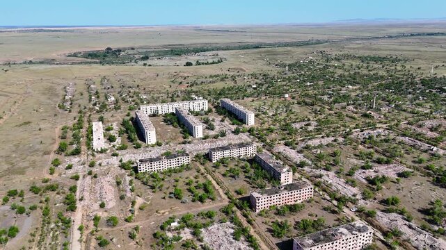 Drone view of the abandoned military town of Chagan. Panorama of ruined panel apartment blocks, demolished houses, piles of stones, and remaining building foundations. Post-apocalyptic landscape 