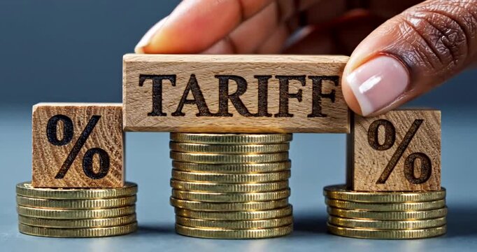 Hand placing wooden tariff percentage blocks on stacks of gold coins showing economic policy concept
