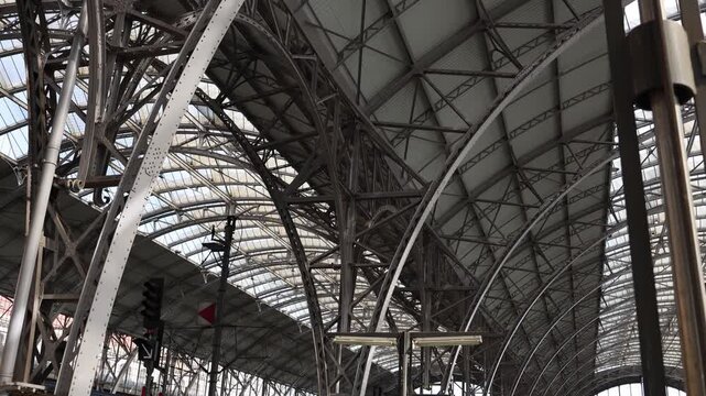 Massive steel roof structure inside historic European railway station showcasing industrial architecture engineering details and urban transportation design