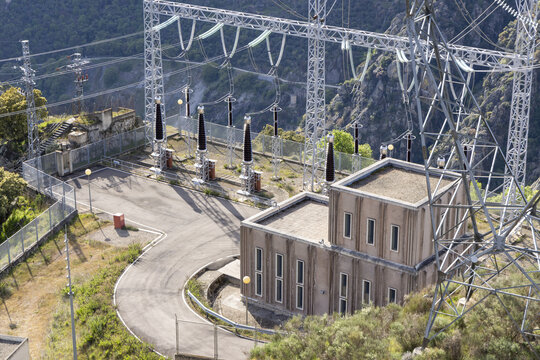View of Aldeadavila II Electrical Substation with high-voltage towers and a concrete building nestled against a rugged mountain slope in Aldeadavila de la Ribera, Castile and Leon, Spain.