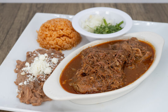 Hearty plate of birria smothered in consome, beans, and rice to satisfy that urge for a Mexican food meal