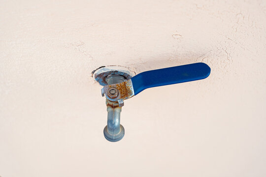 Minimalist photograph of a blue outdoor faucet on a white wall. Image focused on perspective, simple geometry and object recognition for artificial intelligence and computer vision datasets.