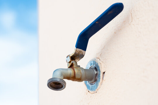 Minimalist image of a blue outdoor faucet with sky background and light wall. Photograph focused on object isolation, perspective and datasets for artificial intelligence.